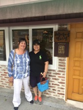 A host and guest in front of a homestay house